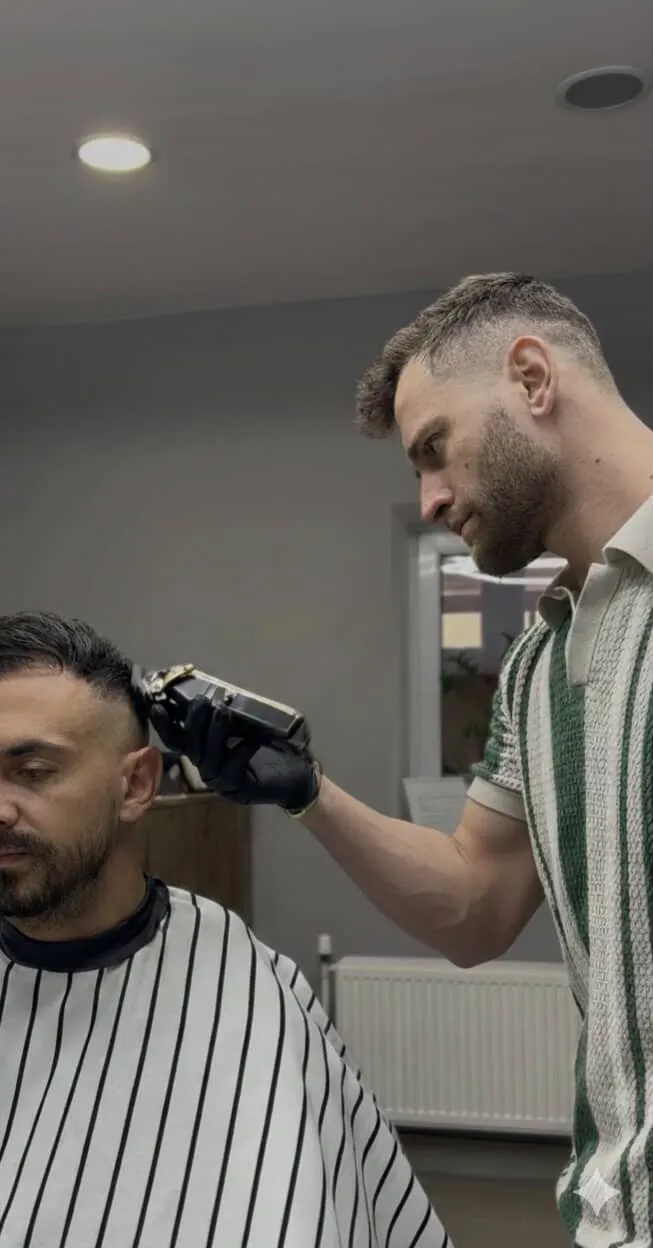 Barber strihajúci klienta strojčekom v East Barber