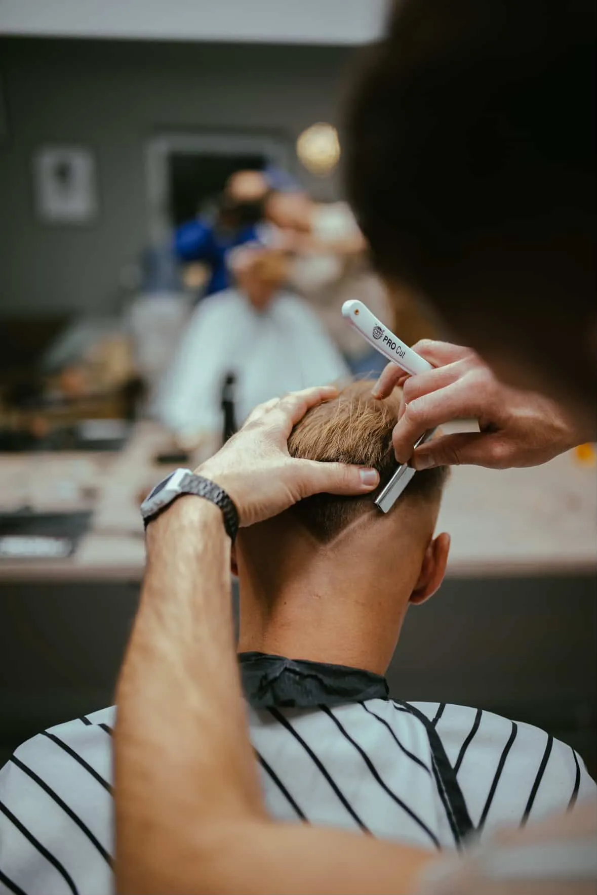 Detail dokončovania strihu žiletkou v East Barber